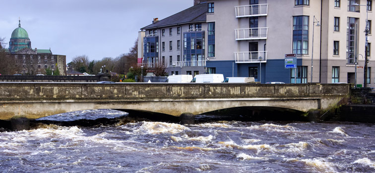 Strong current on river that about to go over bridge and riverbanks in Galway