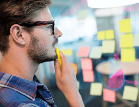 A man looking at post-its on a wall